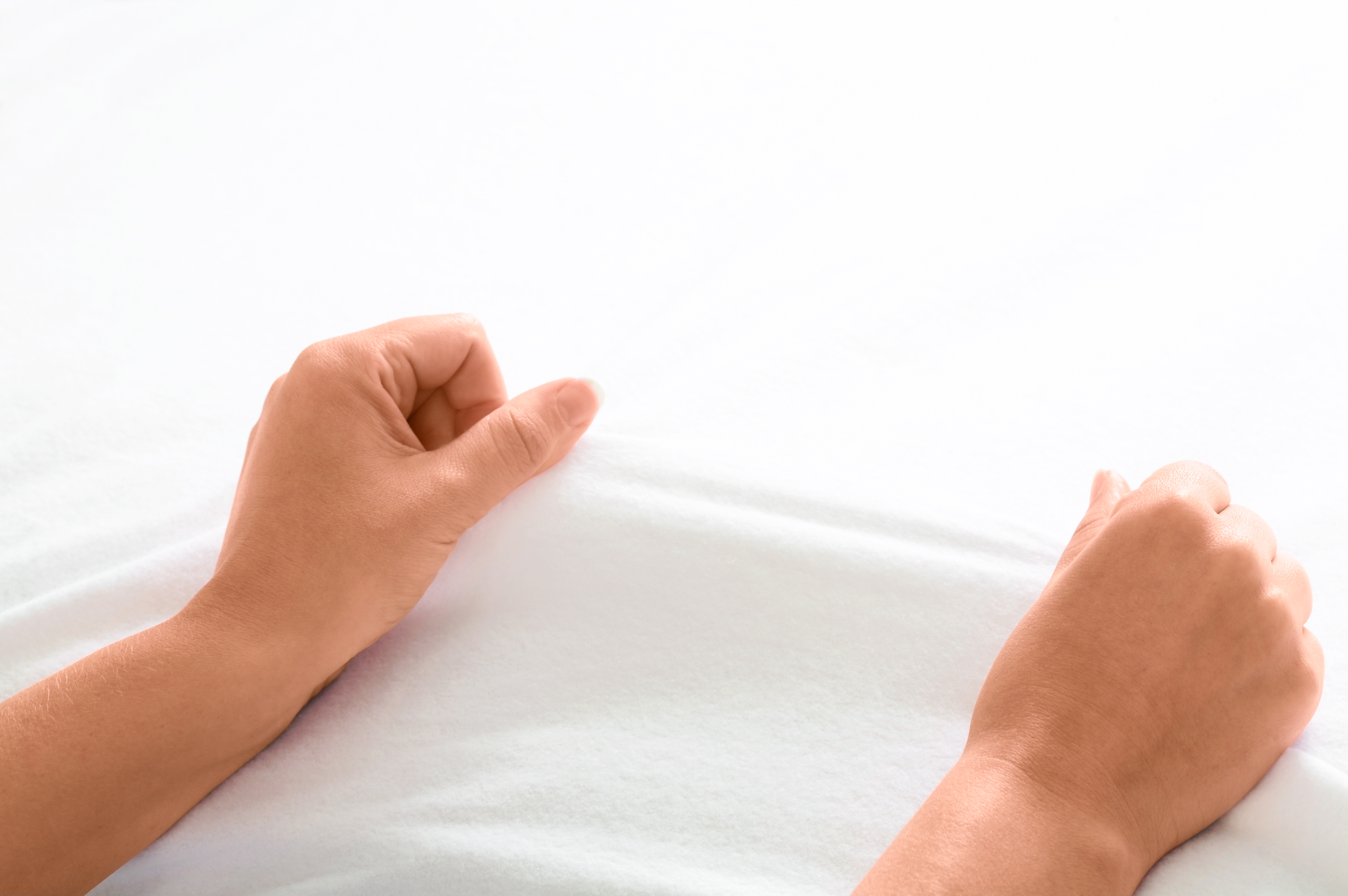 2 Hände halten ein weißes Stretch-Molton-Spannbetttuch in der Hand